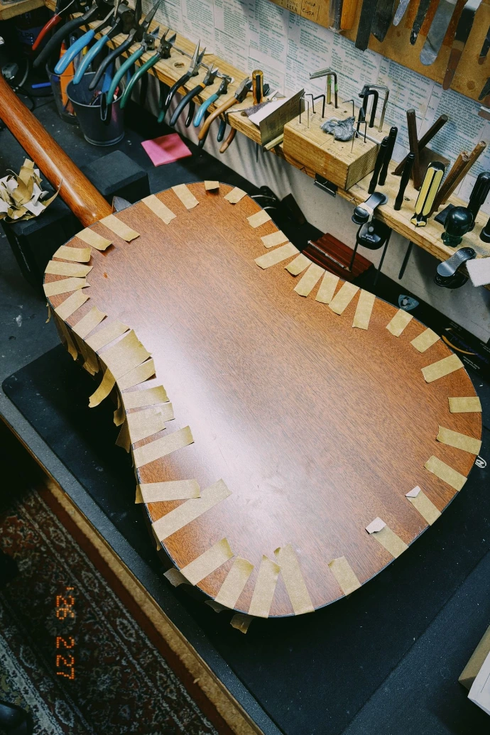 Martin Acoustic guitar upside down with tape on the back as glue is drying